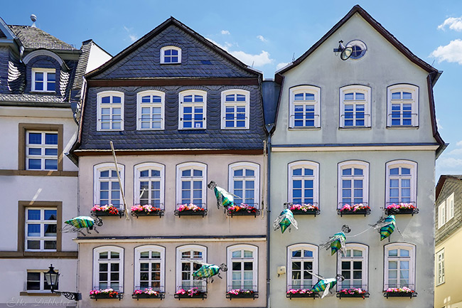 An einer Hauswand sieht man sieben grüne Fliegen.