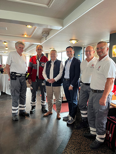 Sechs Personen stehen im Halbkreis auf einem Schiff. Sie lächeln in die Kamera. Darunter sind ehrenamtliche Helfer des DRKs und Oberbürgermeister David Langner sowie Bürgermeisterin Ulrike Mohrs.