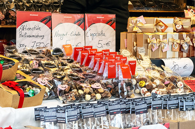 Ein Marktstand der "Art of Chocolate" mit einer großen Auswahl an Pralinenmischungen, Nougat-Spezialitäten und Trinkschokolade am Stiel, festlich verpackt in Schachteln und Beuteln. Foto: Elke Döbbeler