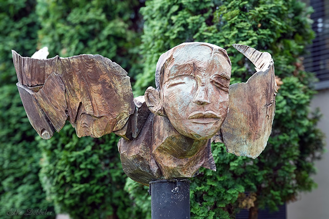 Bronzeskulptur eines Kopfes mit flügelartigen Ohren von Dietrich Klinge, die eine grobe, holzähnliche Oberflächenstruktur aufweist.